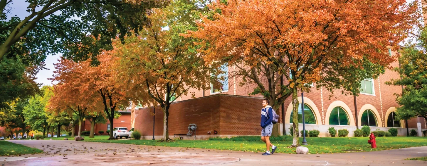 Student walking across campus in the fall.